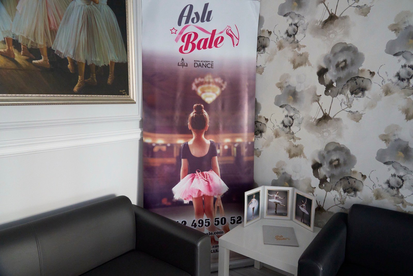 Bekleme köşesinde Aslı Bale afişi, çerçeveli fotoğraflar ve köşe kanepe