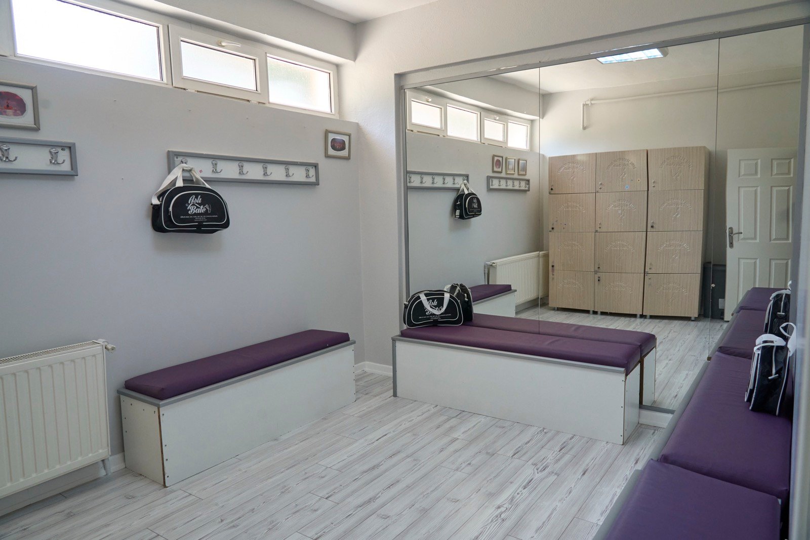 Öğrenci soyunma odası: aynalı duvar, mor oturma bankları ve dolaplar
