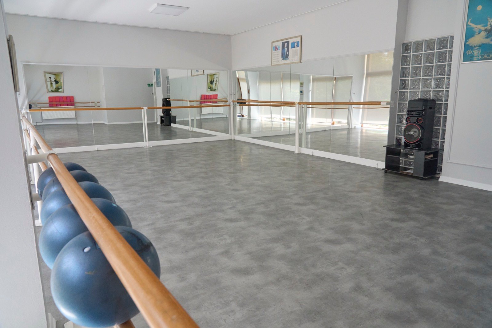 Stüdyoda ahşap bar, duvar boyu ayna ve barın altında sıralanmış pilates topları